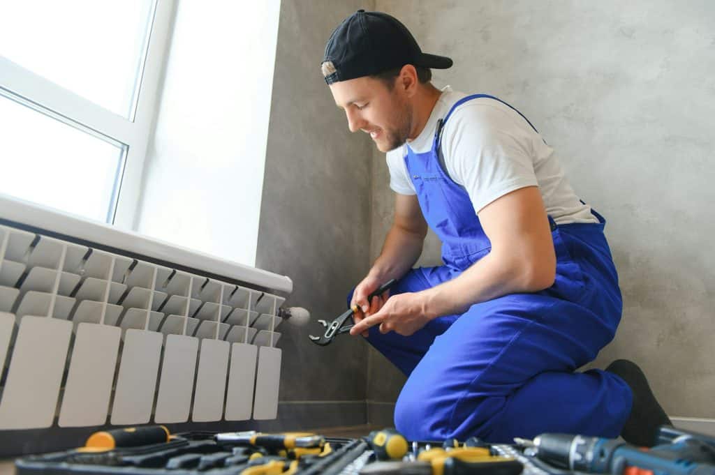 Heating system installation and maintenance service. plumber installing radiator.
